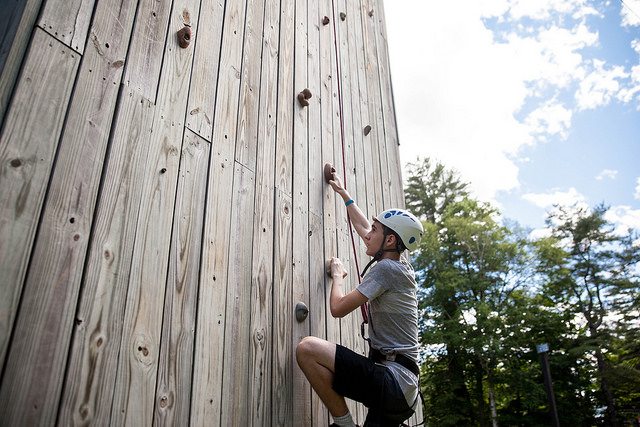 Teen climbing a climbing tower.