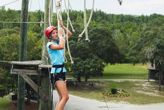 girl crossing the high ropes course.