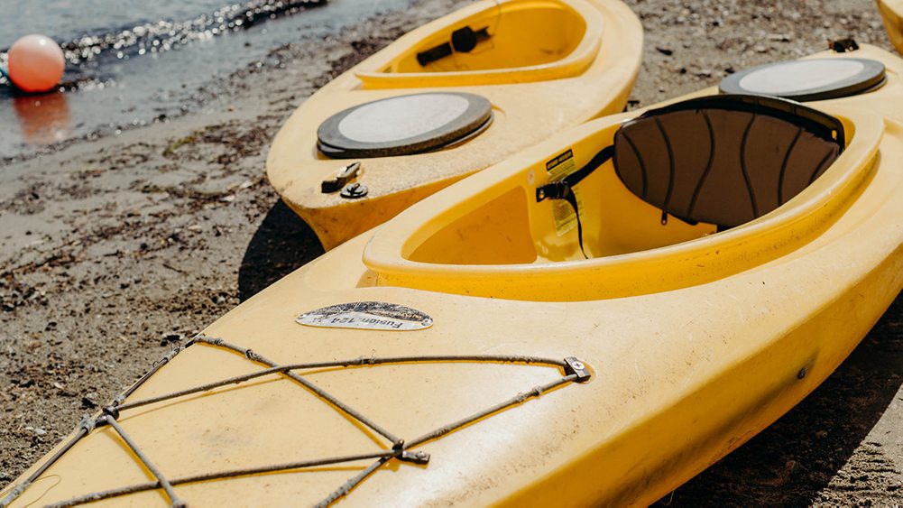 two yellow kayaks on a beach.