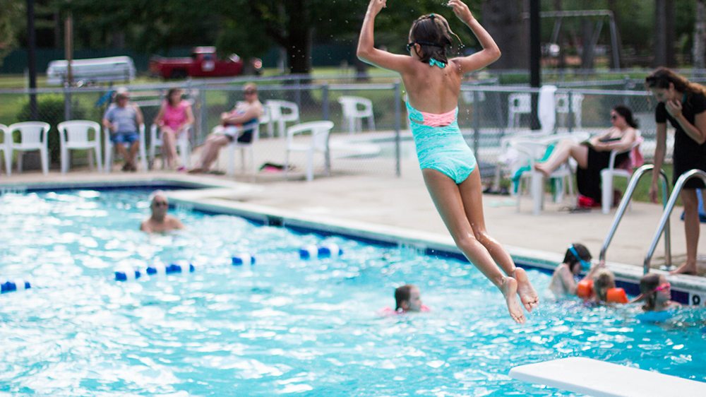 Girl jumping off a diving board into a pool.