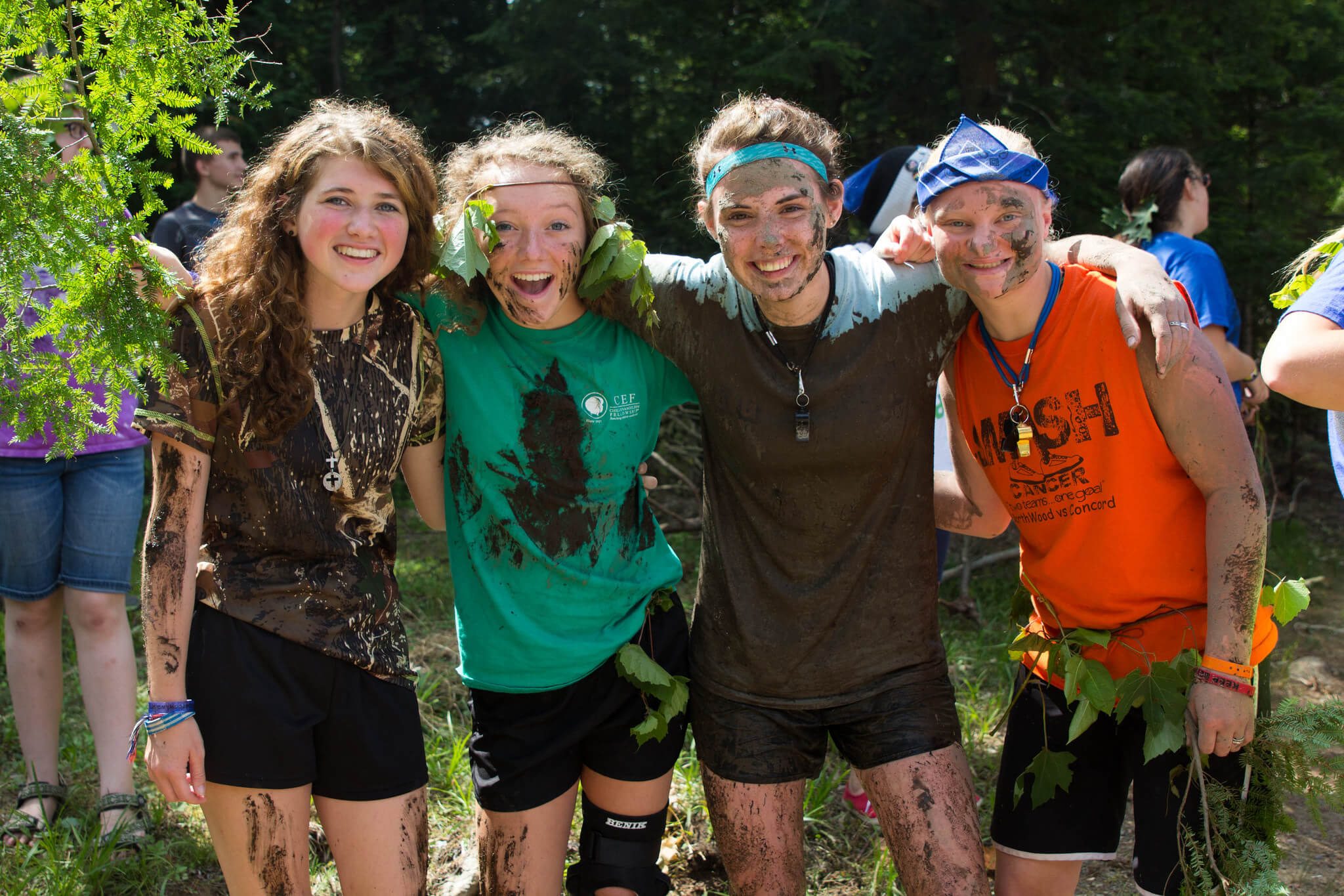 women covered in mud and twigs smiling