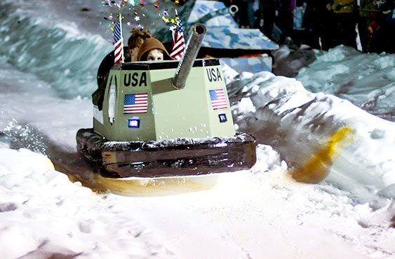 cardboard sled in the shape of a tank sliding down a hill.