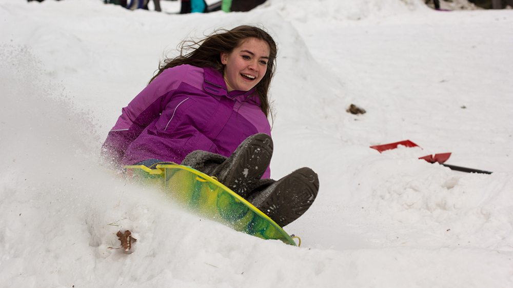 kid sliding down a hill on a sled