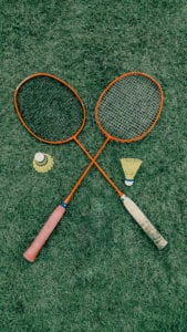 Badminton rackets and birdies on grass.