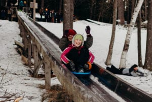 Two girls sliding down an ice chute.